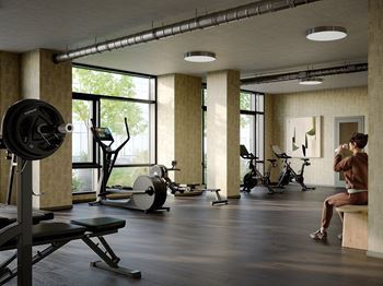 A person is sitting on a bench in a gym with a barbell on a squat rack.