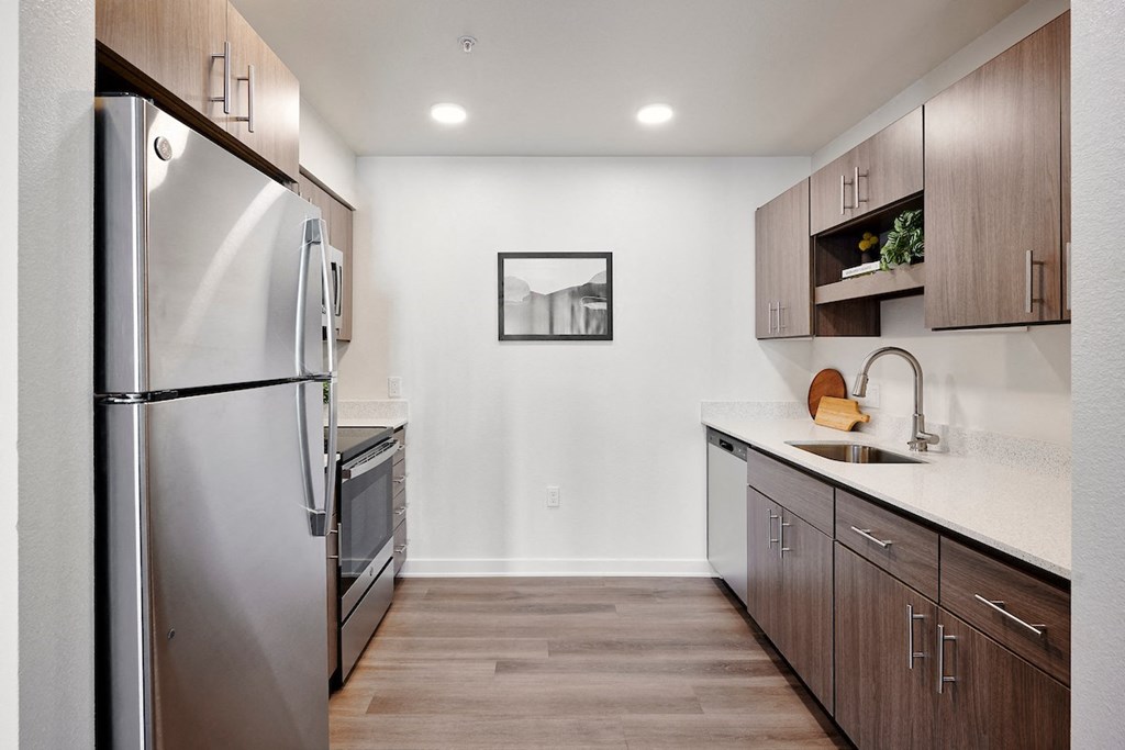 an empty kitchen with stainless steel appliances and wooden cabinets