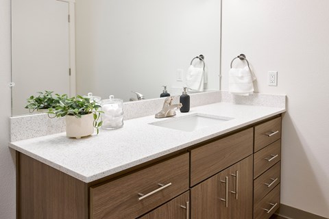 A bathroom with a white countertop and brown cabinets.