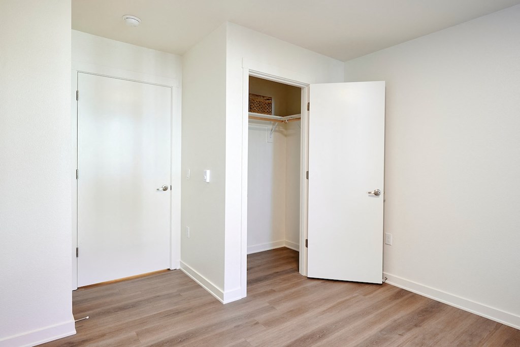 an empty bedroom with white doors and a closet
