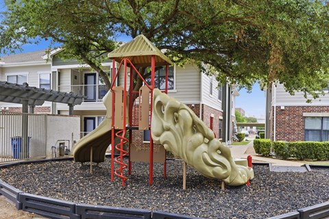 A playground with a slide and a tree in the background.