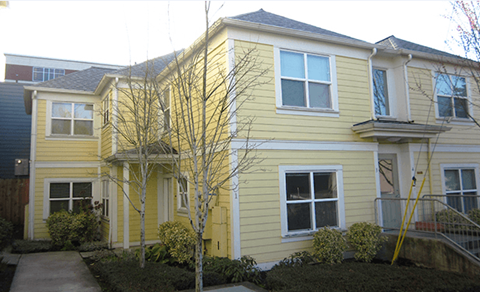 a yellow house with a sidewalk in front of it