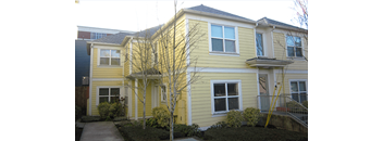 a yellow house with a sidewalk in front of it