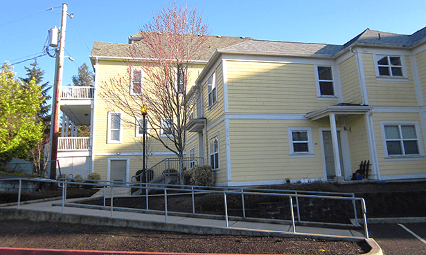 a yellow house with a sidewalk in front of it