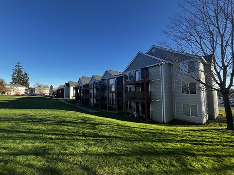 A large grassy field in front of apartment buildings.