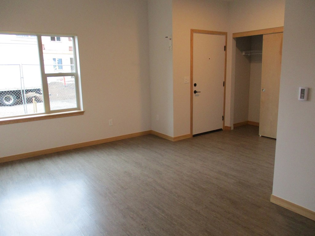 an empty living room with wood floors and a window