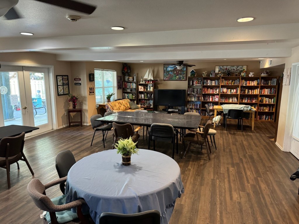 A room with a table, chairs, and a bookshelf.