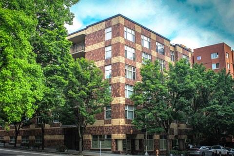 A tall building with a lot of windows and trees in front of it.