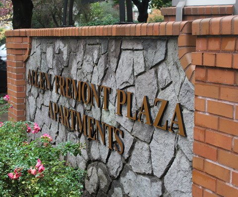 A sign for the "Avenue Fremont Plaza Apartments" is displayed on a stone wall.