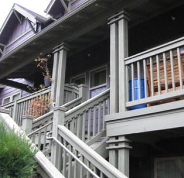A porch with a white railing and a blue planter.
