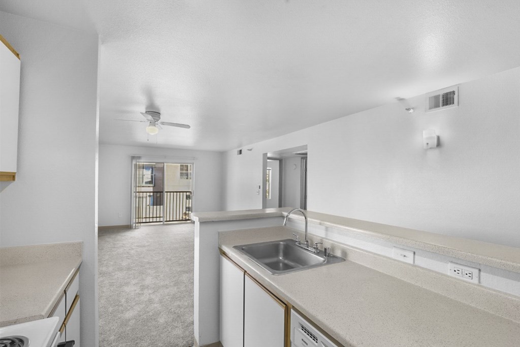 A kitchen with white cabinets and a stainless steel sink.