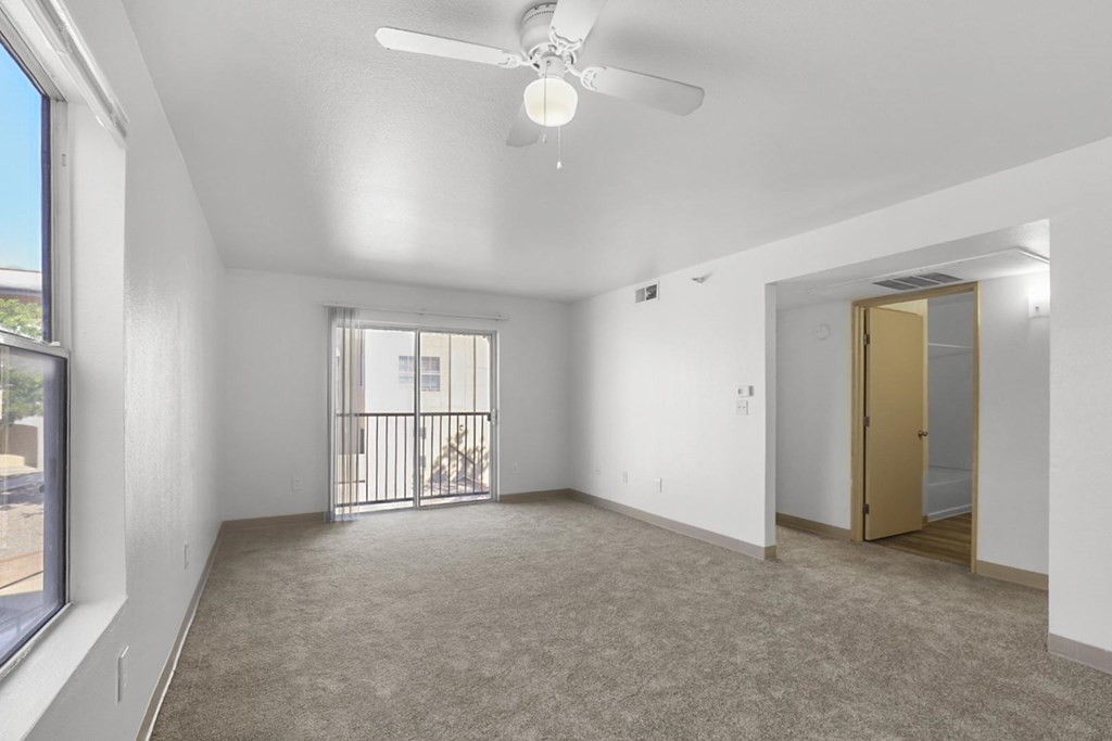 A room with a ceiling fan and a door leading to another room.