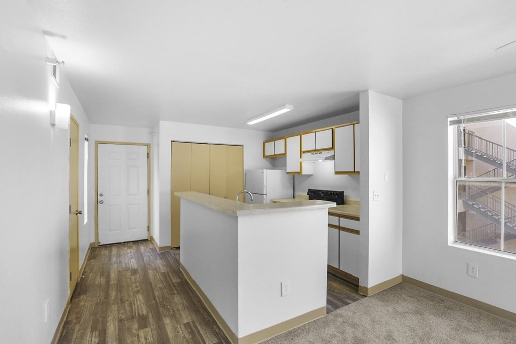 A kitchen with white cabinets and a wooden floor.