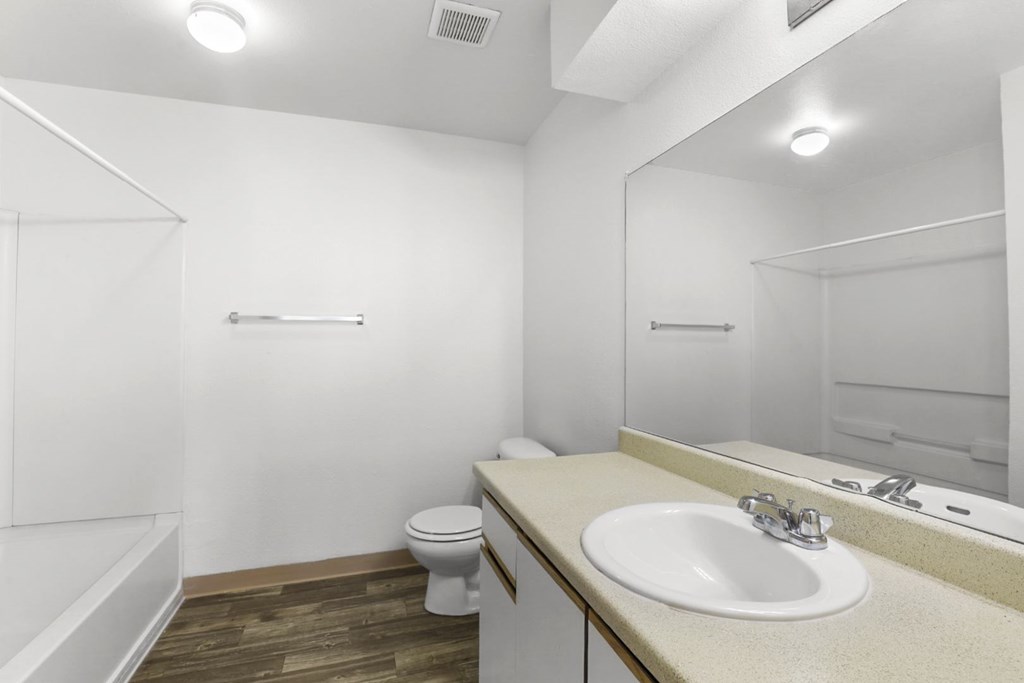 A white bathroom with a toilet, sink, and mirror.