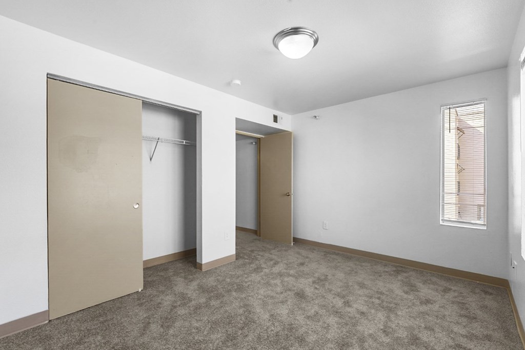 A room with a carpeted floor and two doors.