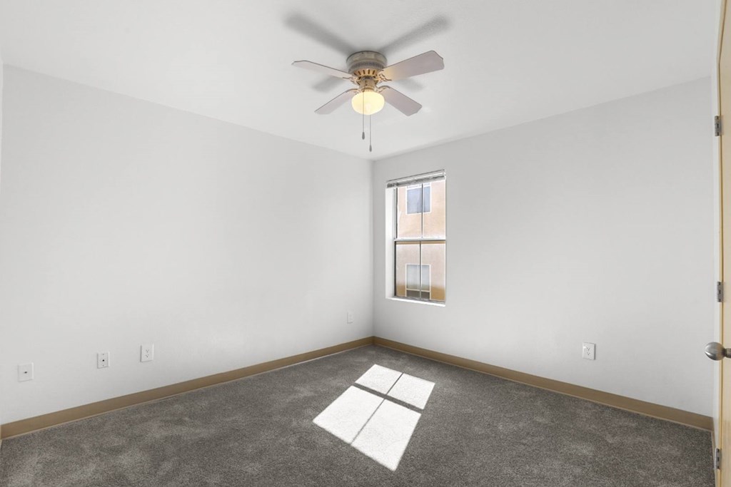 A room with a ceiling fan and a window.