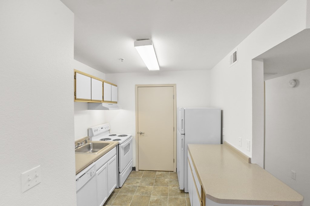 A kitchen with white cabinets and a beige countertop.