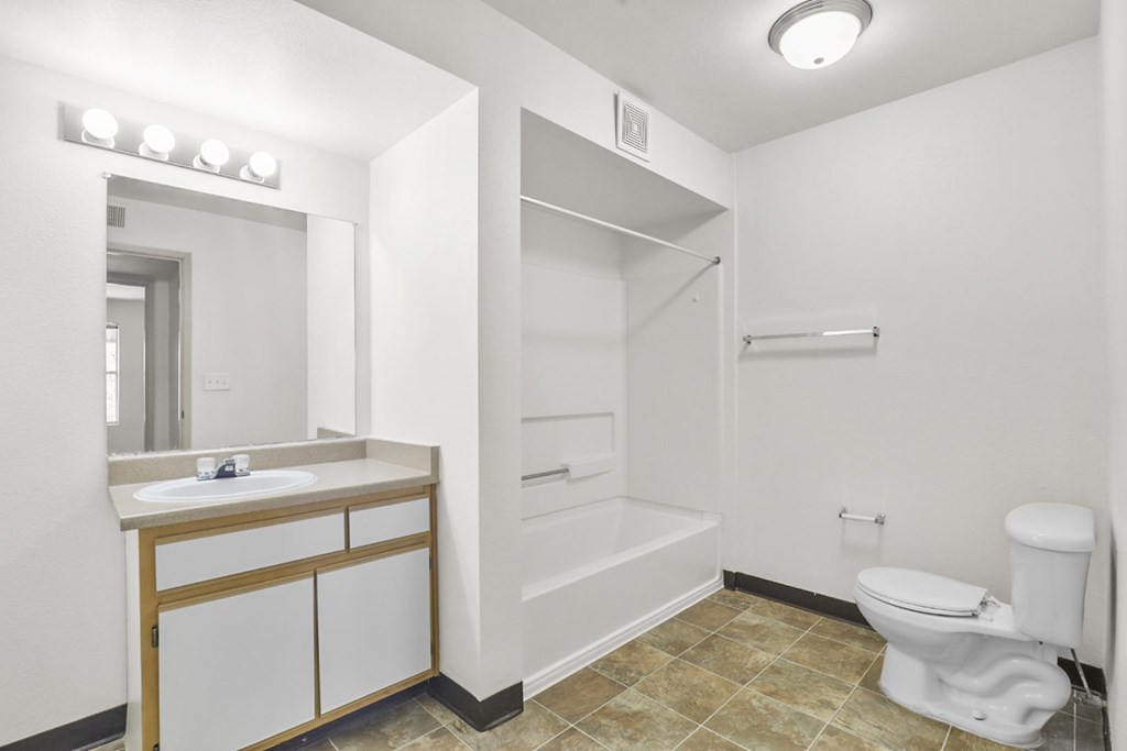 A bathroom with a toilet, sink, and mirror.
