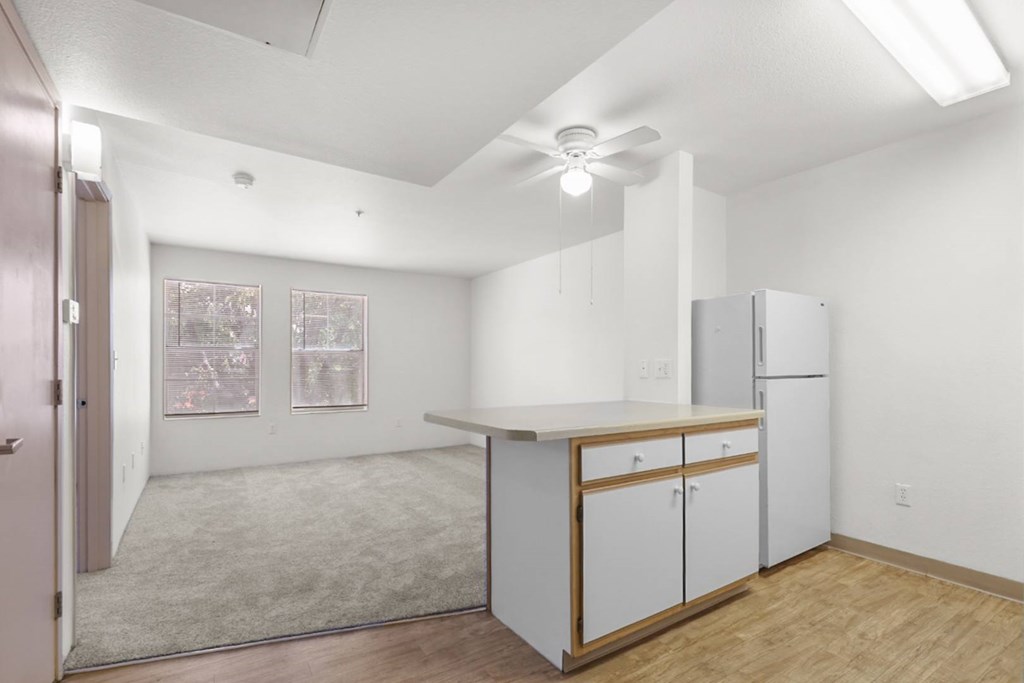A kitchen with white cabinets and a ceiling fan.