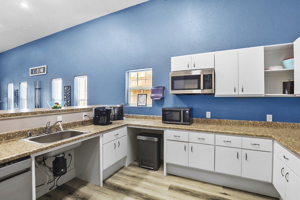 A kitchen with white cabinets and a blue wall.