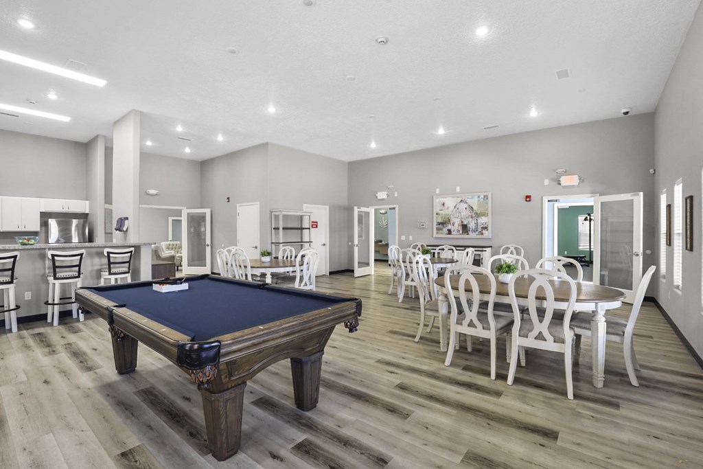 A billiard table is in the middle of a room with a dining table and chairs.