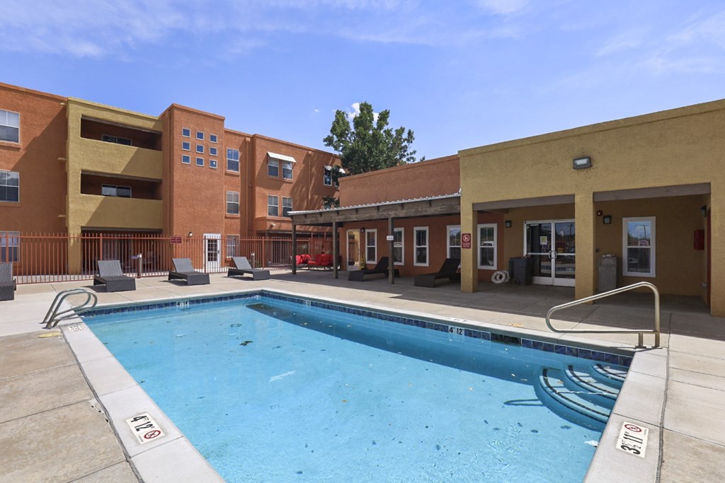A swimming pool in front of a building with a red and yellow exterior.