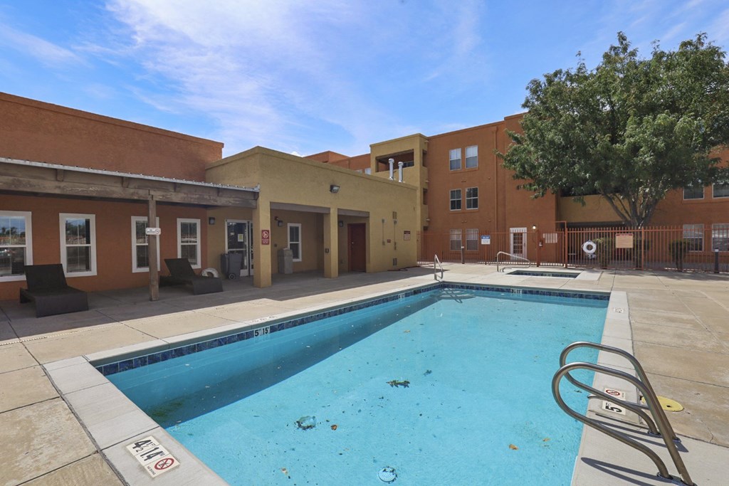 A pool in front of a building with a tree.