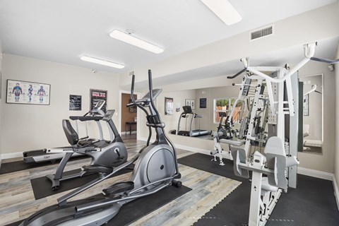 A gym with a variety of equipment including treadmills, elliptical machines, and weight machines.