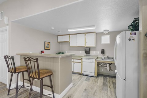 A kitchen with a white refrigerator and wooden chairs.