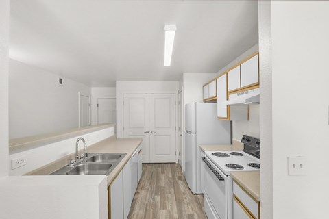 A white kitchen with a sink, stove, and cabinets.