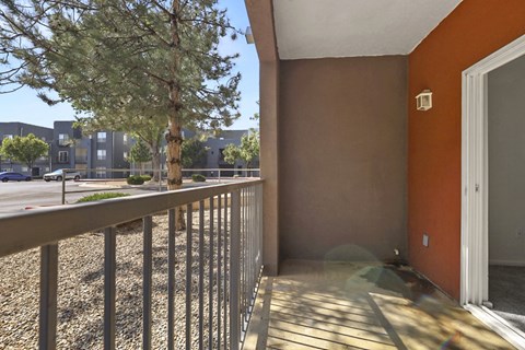 A balcony with a metal railing and a tree in the background.
