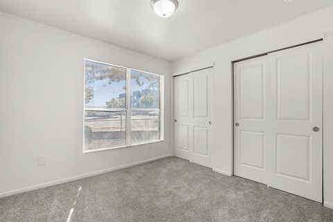 A room with a large window, two doors, and a car parked outside.