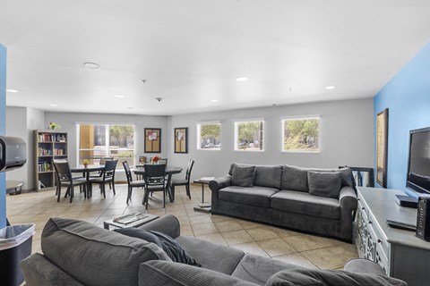 A living room with grey couches and a dining table.