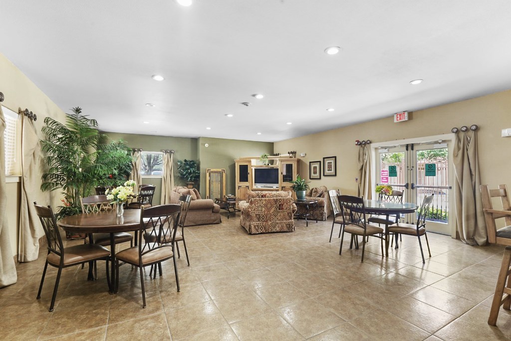 A spacious room with a dining table and chairs, a sofa, and a television.
