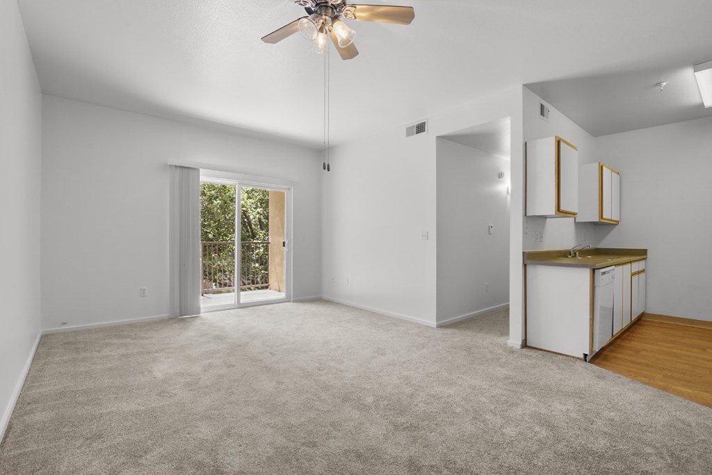 A spacious room with a ceiling fan and a small kitchenette.