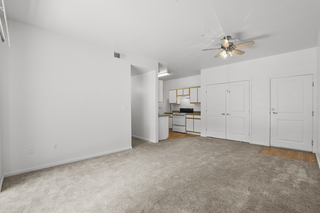 A spacious room with a ceiling fan and a desk with a chair.