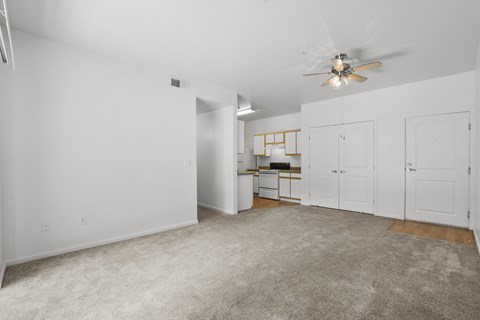 A spacious room with a ceiling fan and a desk with a chair.