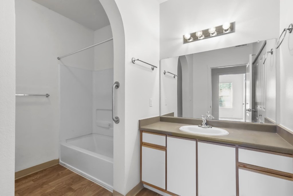 A bathroom with a sink, mirror, and shower.