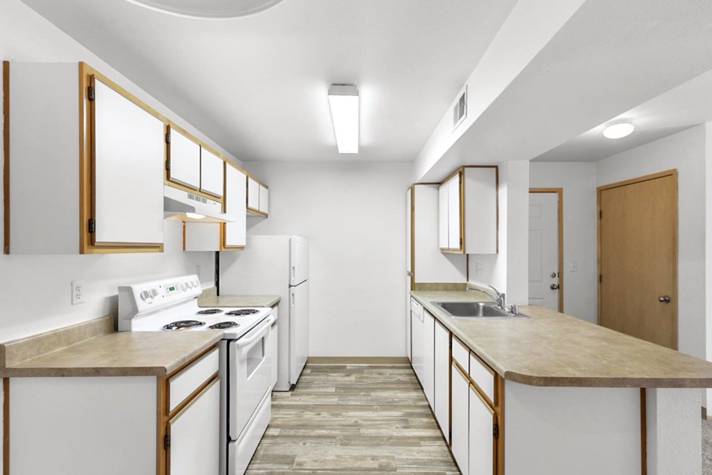 A kitchen with white appliances and wooden cabinets.