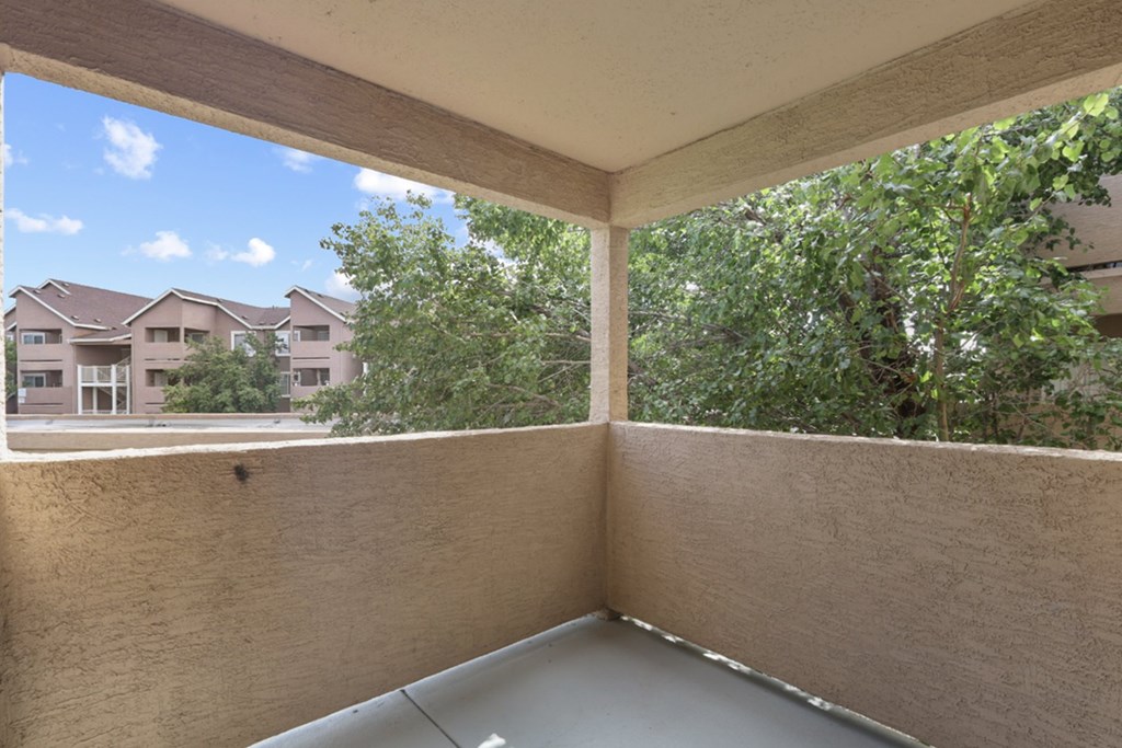 A balcony with a view of apartment buildings and trees.