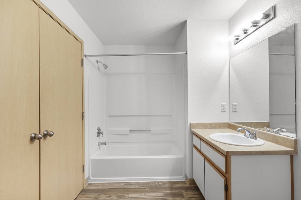 A bathroom with a wooden door and a white bathtub.