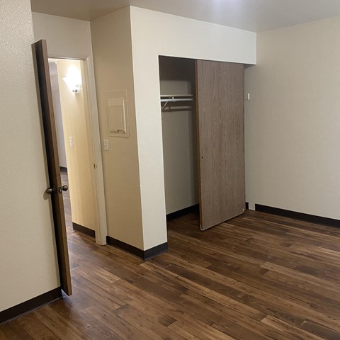 a bedroom with a door to a closet and a hallway with wood flooring