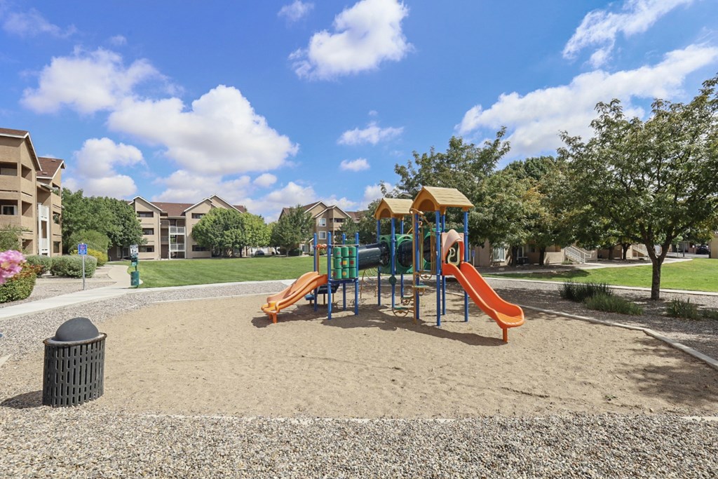 A playground with a yellow slide and a blue and yellow swing set.