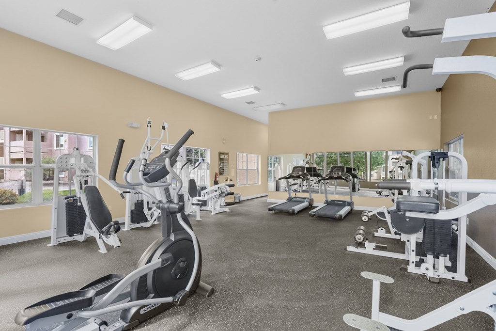 A spacious gym with a variety of equipment including treadmills, stationary bikes, and weight machines.