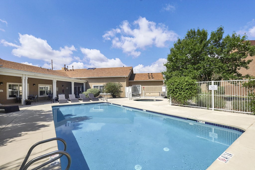 A swimming pool surrounded by a fence and a building in the background.