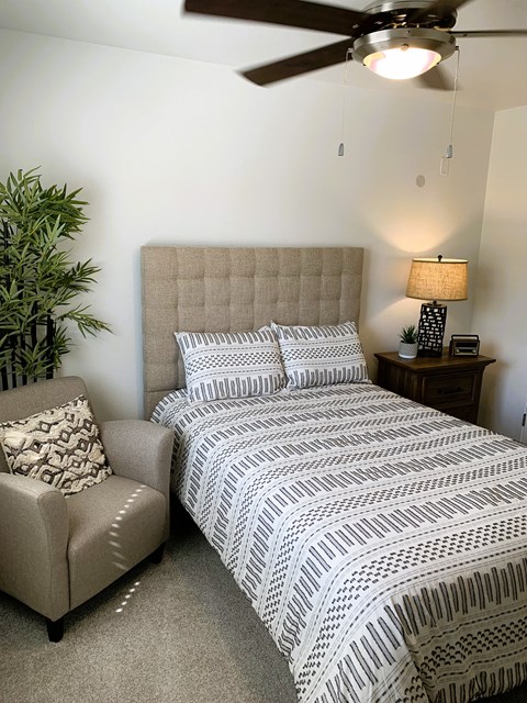 a bedroom with a bed and a chair and a ceiling fan