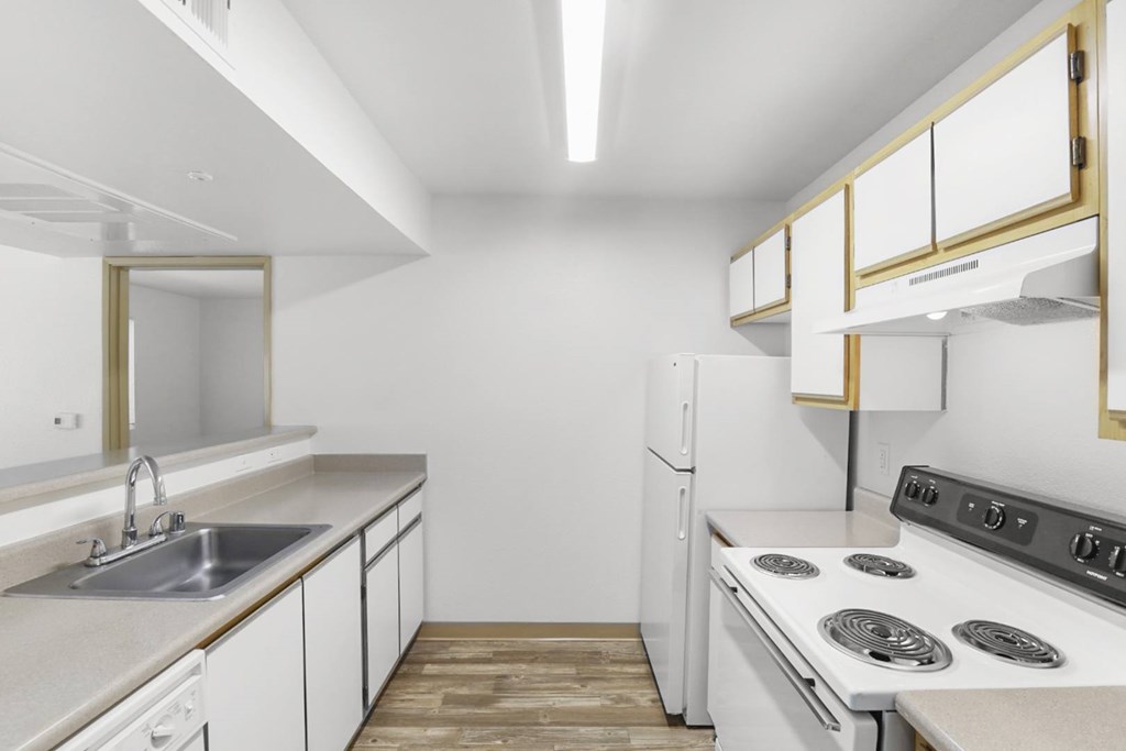 A white kitchen with a stove top oven and a sink.