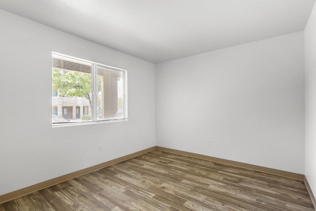 A room with a window and wooden flooring.