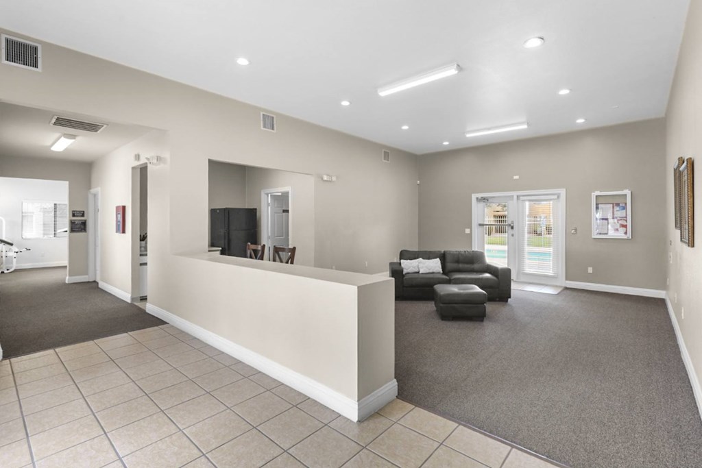 A spacious living room with a grey carpet and a white sofa.
