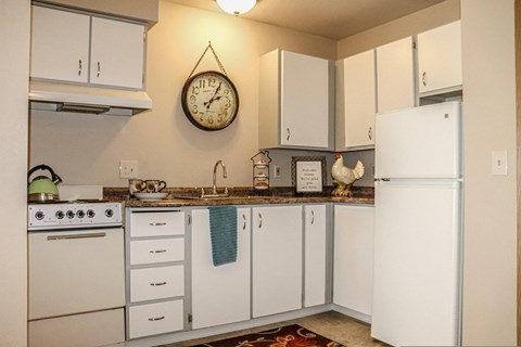 a kitchen with white cabinets and a clock on the wall